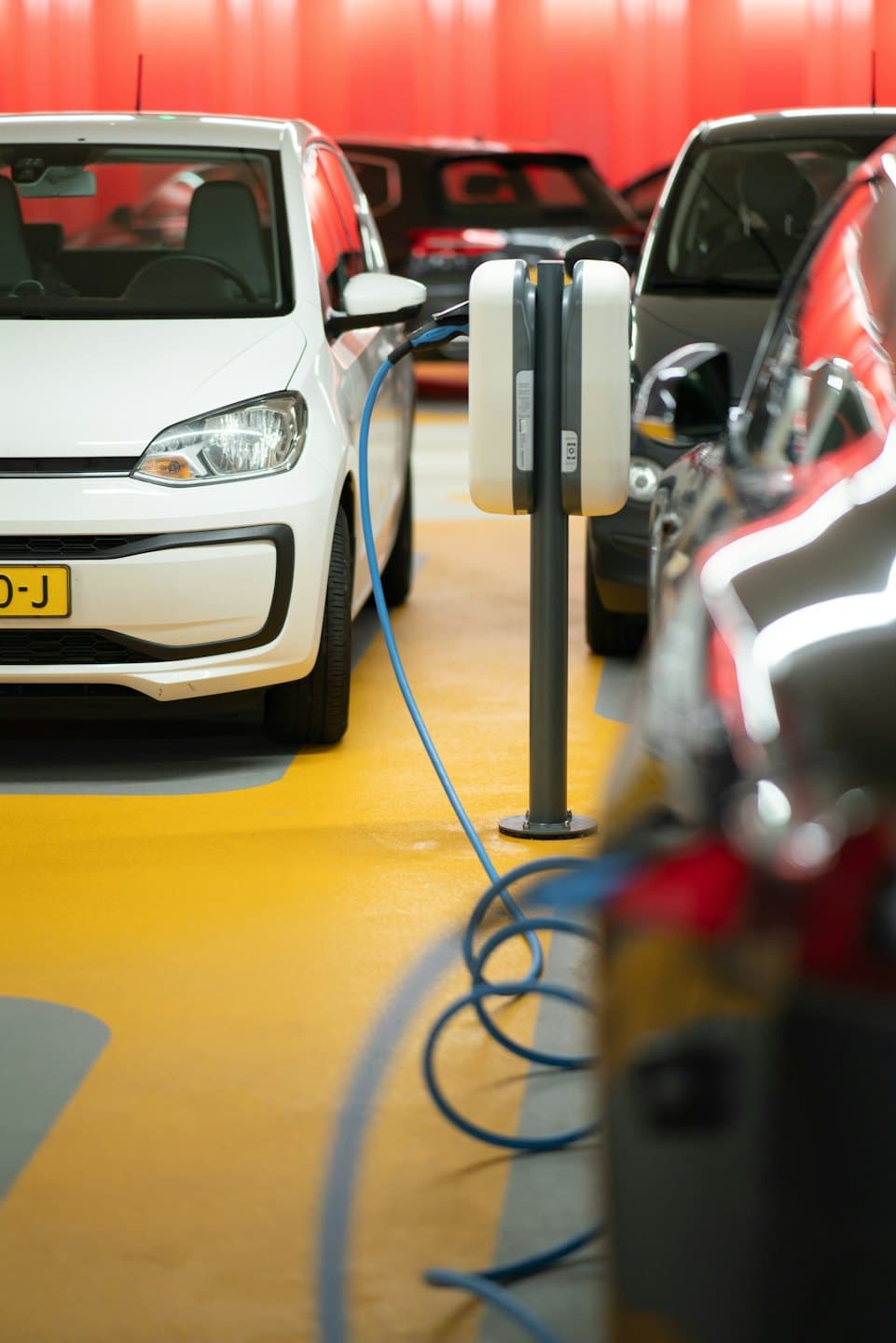White electric car charging at a modern station on a yellow floor.