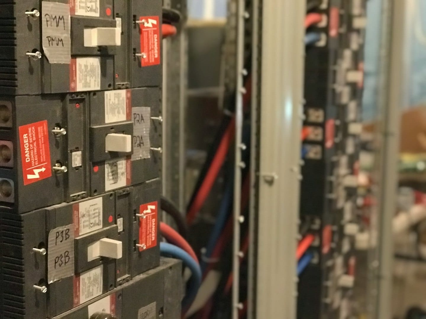 Electrical circuit breakers with white toggle switches and red labels.