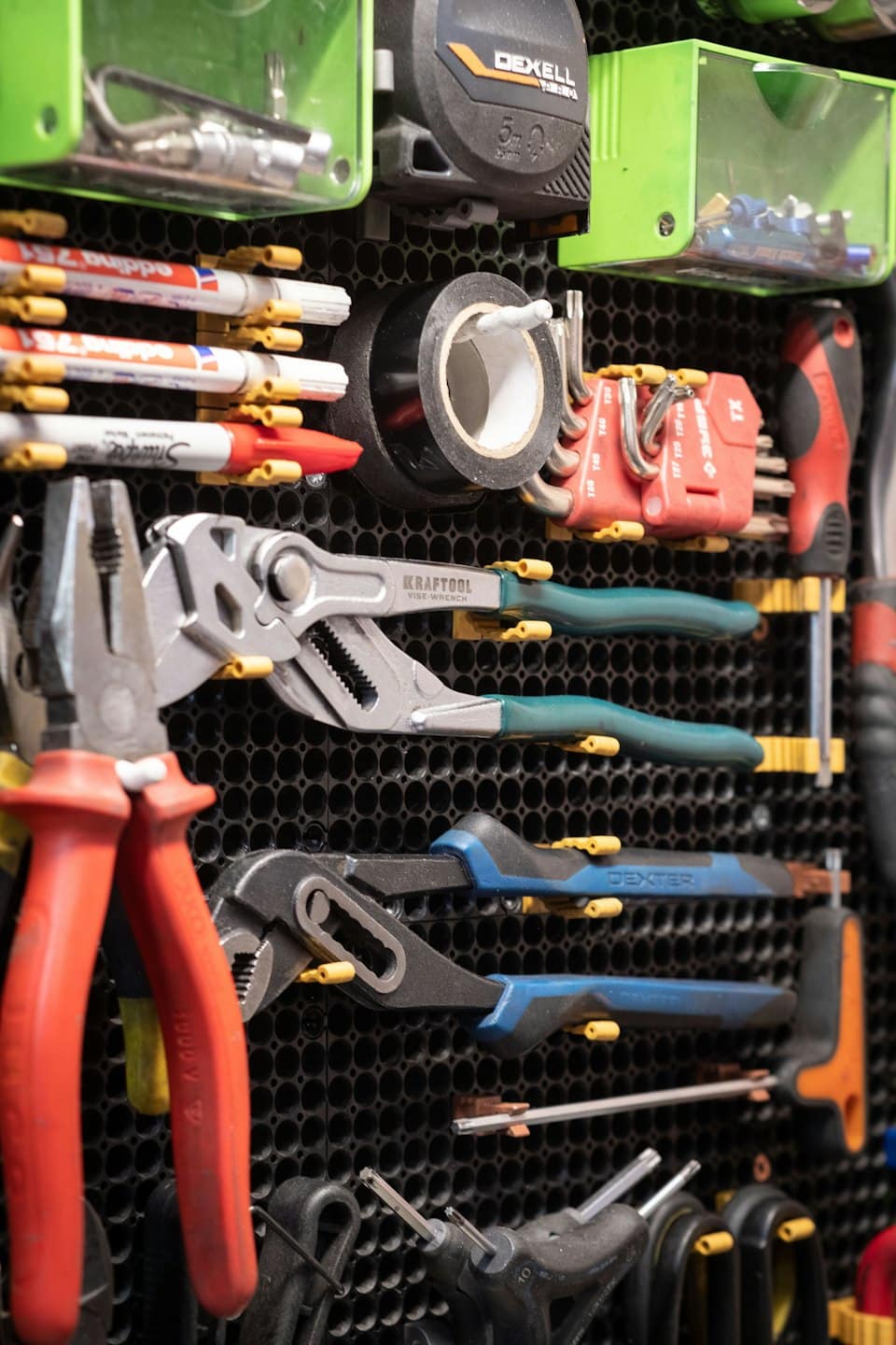 Hand tools organized on a perforated wall pegboard.