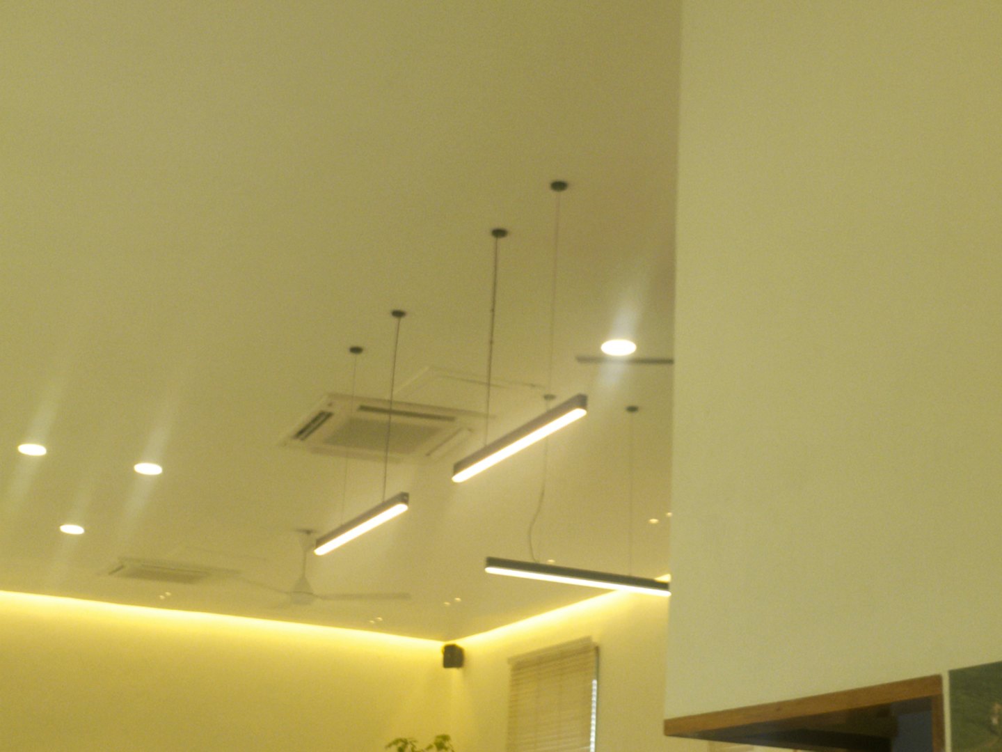 Modern ceiling featuring linear pendant lights and recessed spotlights.